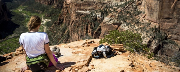 Photo of woman sitting on top of rock overlooking large valley in a park